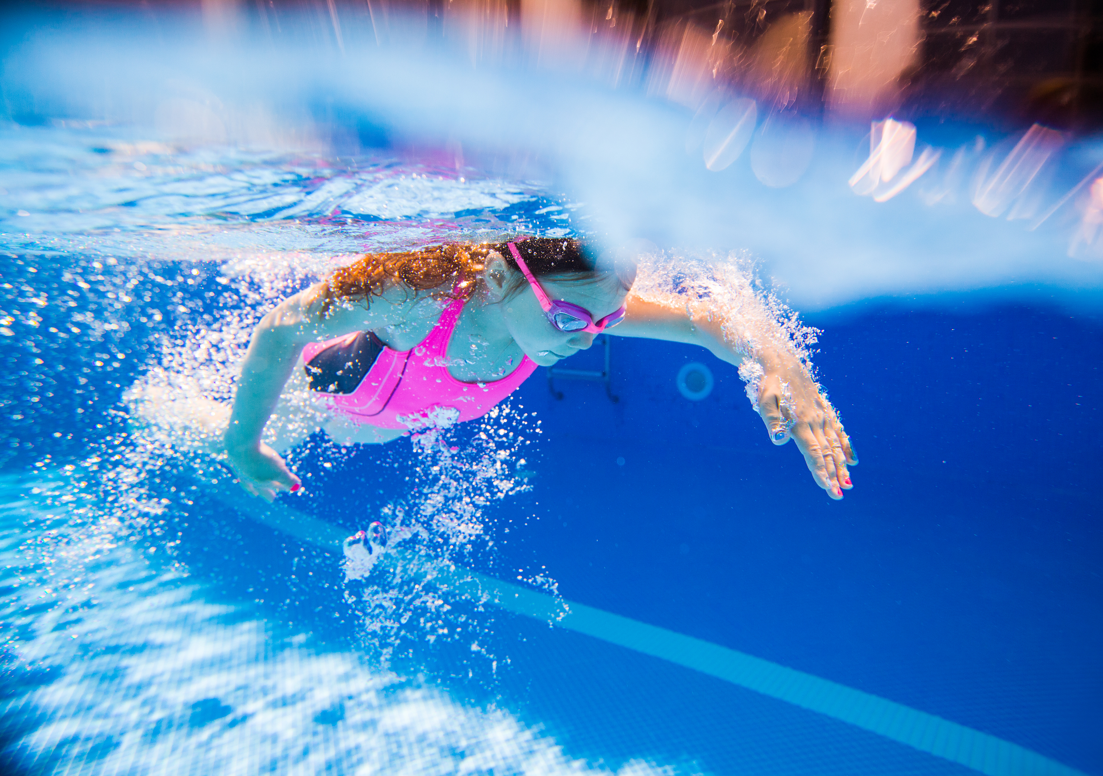 Little girl swimming crawl in pool.