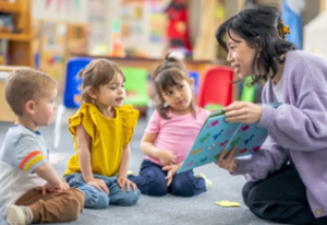 Female adult reading book to group of toddlers