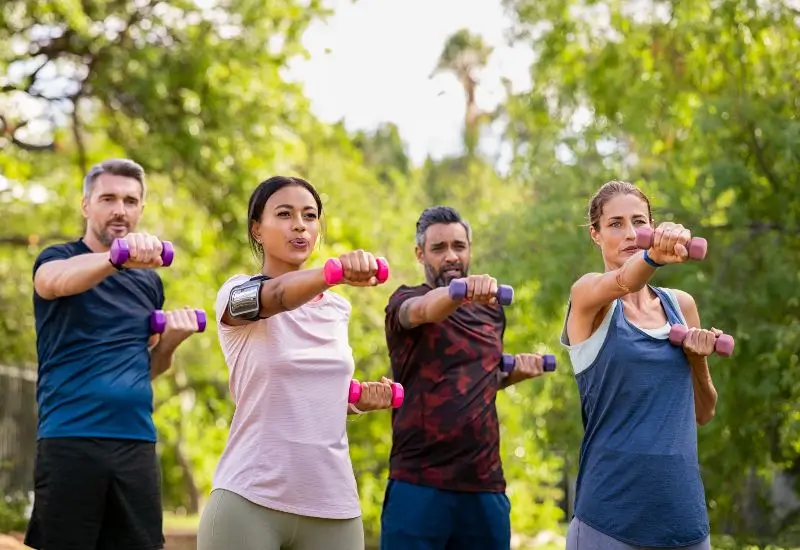 Group of adults exercising outside with dumbbells