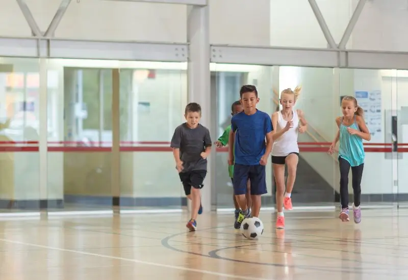 Group of kids playing soccer inside YMCA gym