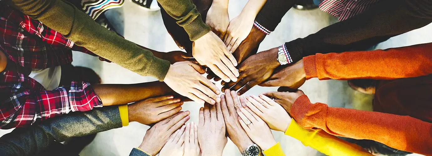 Group of people putting hands in the middle