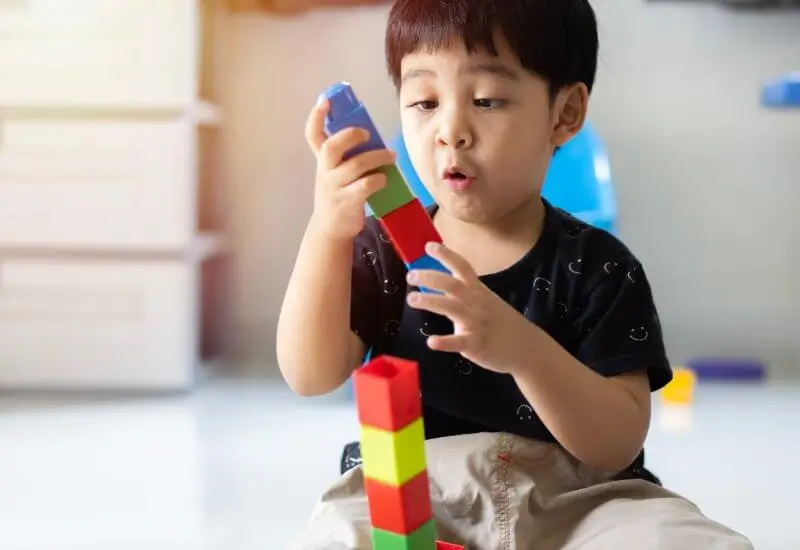 Toddler boy playing with plastic construction blocks