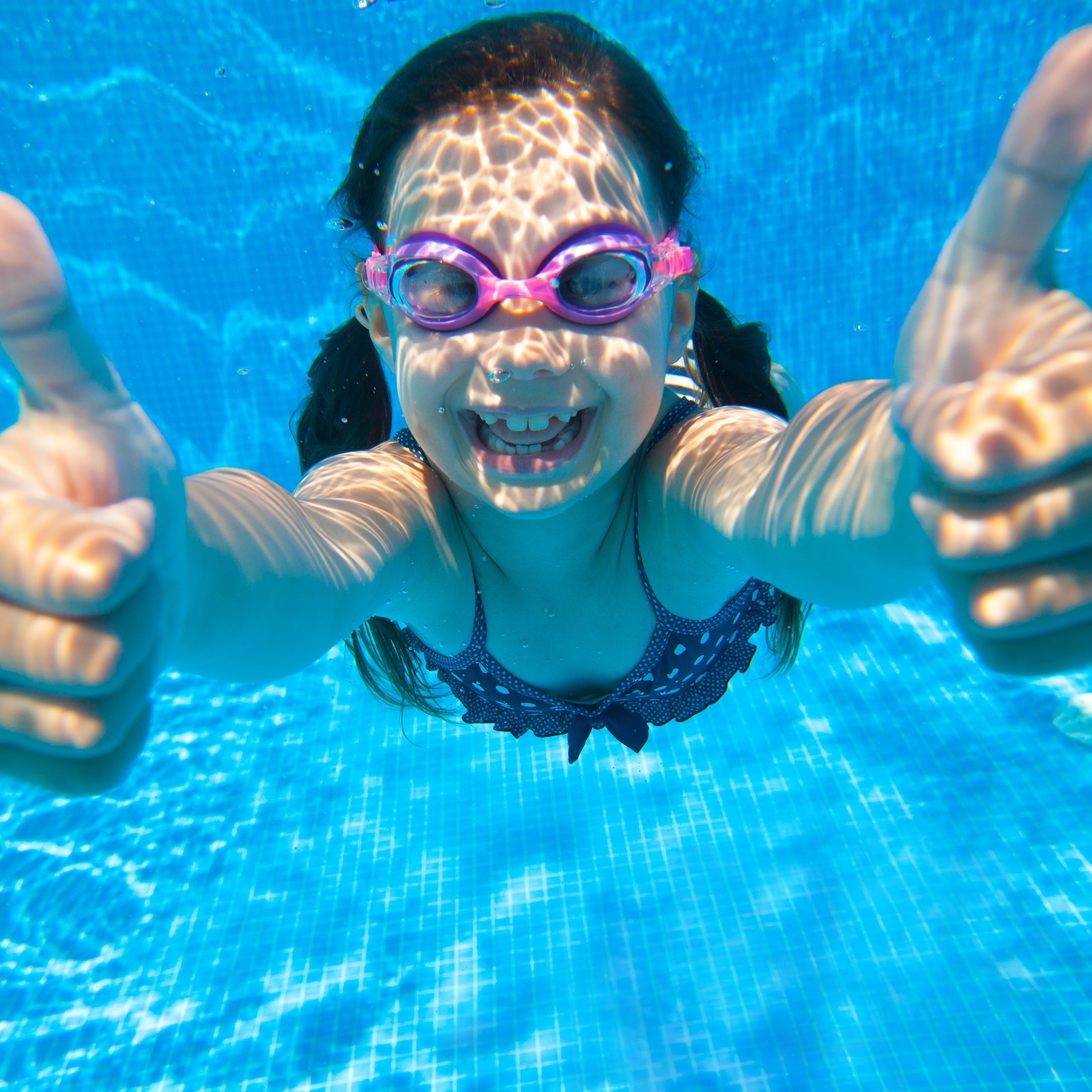 little girl dives into the water and shows the gesture OK