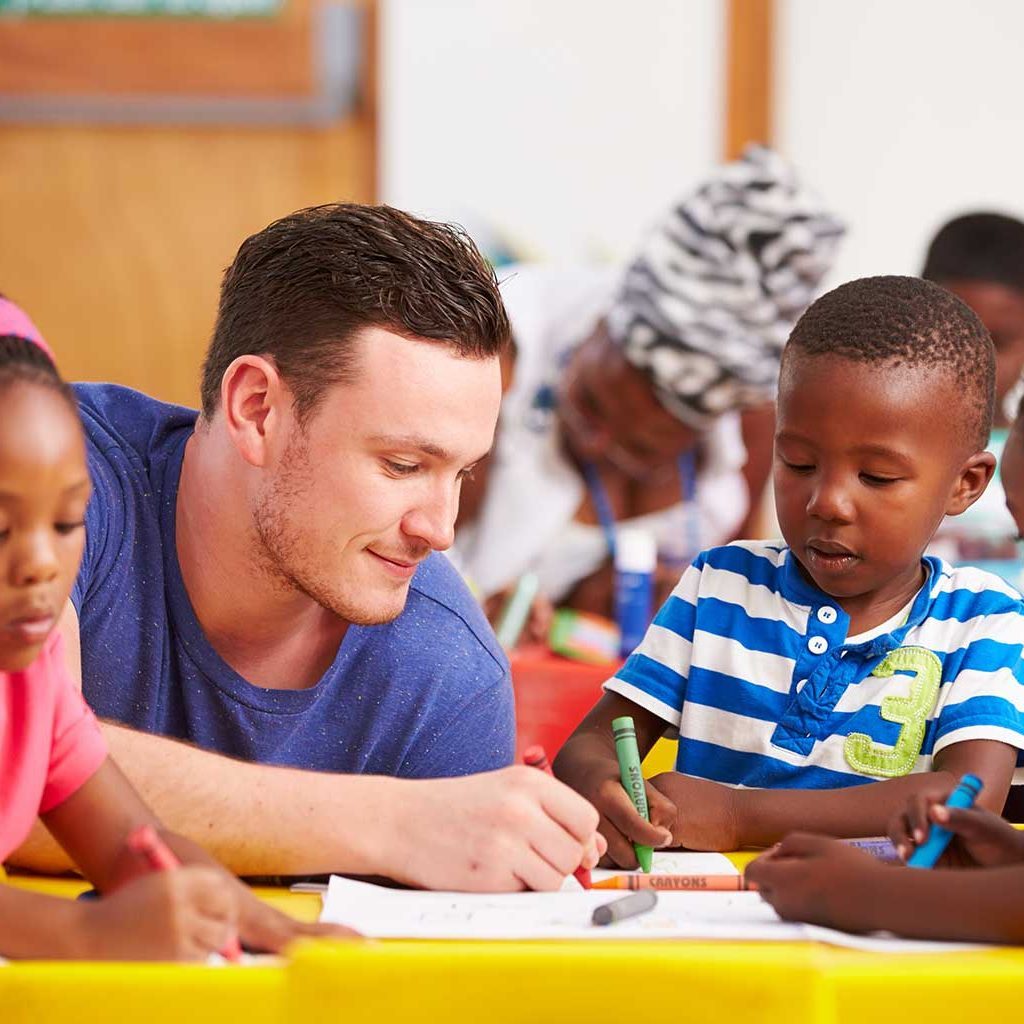 A teacher helping a child to color on the drawing paper