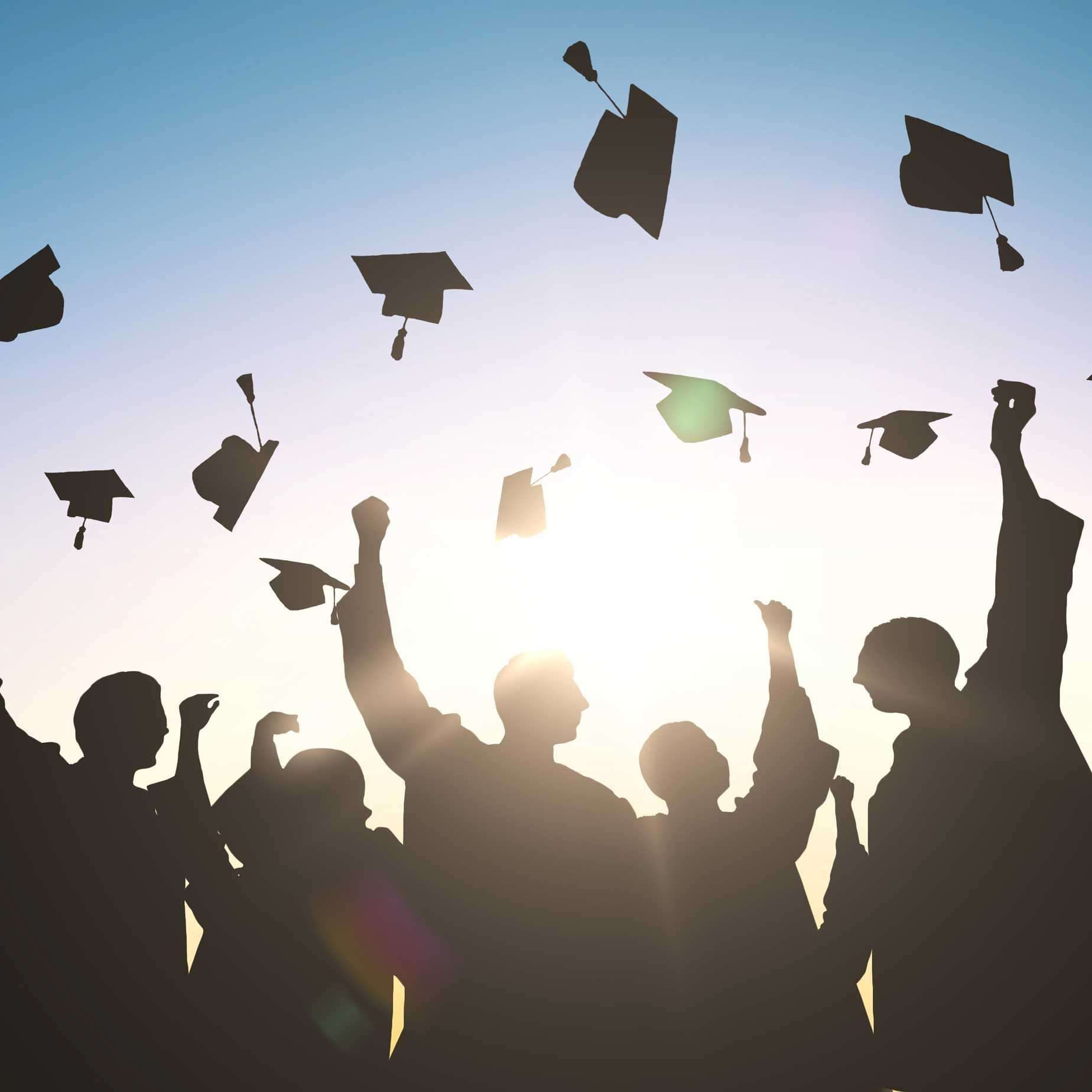 A group of students throwing their caps up during a graduation ceremony in Central Massachusetts